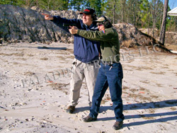 NRA gun safety rule 1: Always keep the gun pointed in a safe direction. Joe Katz is showing Janet Katz the safe direction on this shooting range. Note the directly rooftop behind them, the low berm to the side, and the driveway behind it. Those directions are not safe. NRA gun safety rule 1: Always keep the gun pointed in a safe direction. Joe Katz is showing Janet Katz the safe direction on this shooting range. Note the directly rooftop behind them, the low berm to the side, and the driveway behind it. Those directions are not safe.
